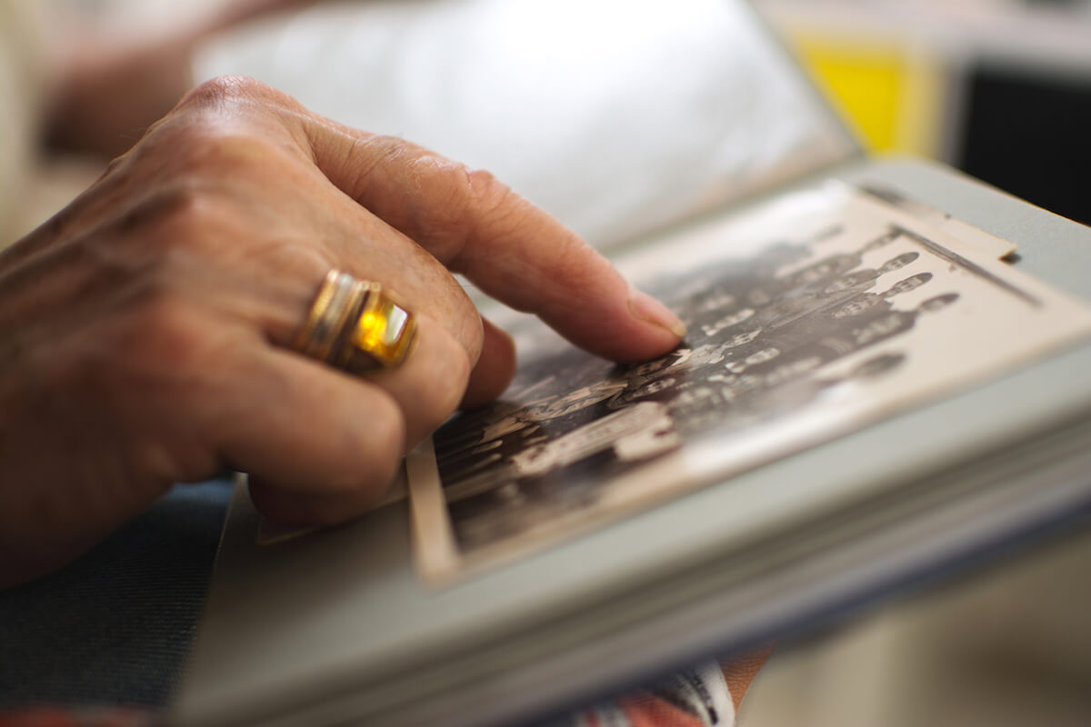 Close up of a photo in photo album, hand pointing to person in photo-Dementia Care